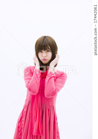 站立在照相機的眼睛的一位桃紅色微型一件式小姐，當接觸她的頭髮用在白色背景前面時的兩隻手 17442061