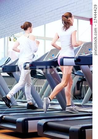 Two young sporty women run on machine Two young sporty women run on machine 17444429
