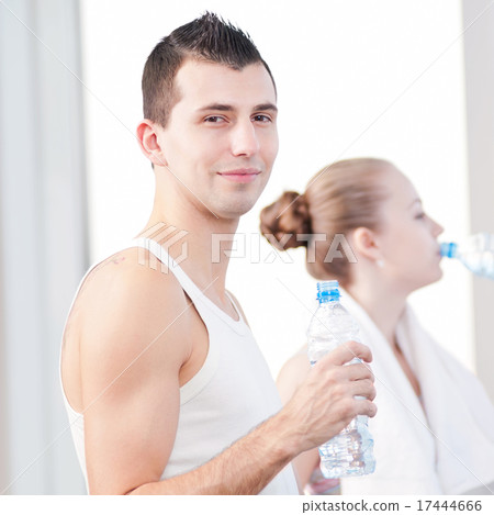 Man and woman drinking water after sports in gym 17444666
