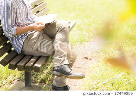A man reading with a park bench 17449899