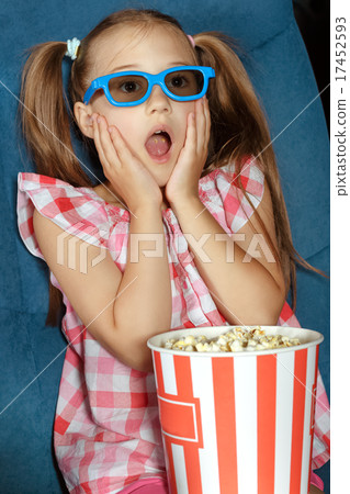 Little girl eating popcorn during a movie 17452593