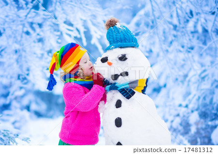 Little girl building a snow man in winter 17481312