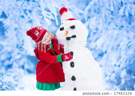 Little girl building a snow man in winter 17481329