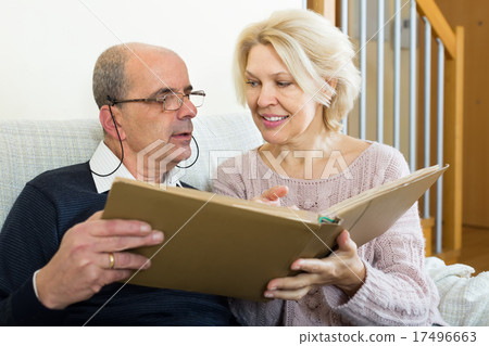 Senior spouses with picture album indoor 17496663