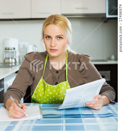Woman reading document at kitchen 17496974