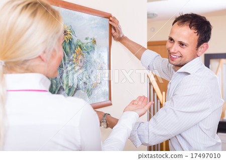 Couple hanging art picture in frame 17497010