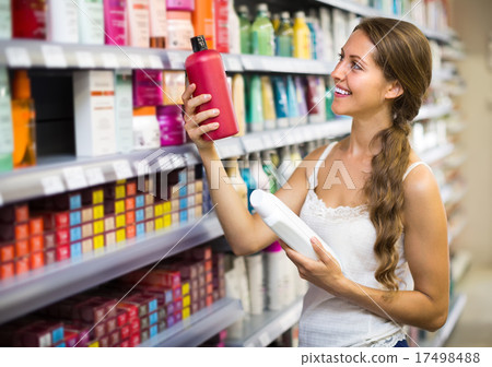 Woman choosing shampoo at store. 17498488