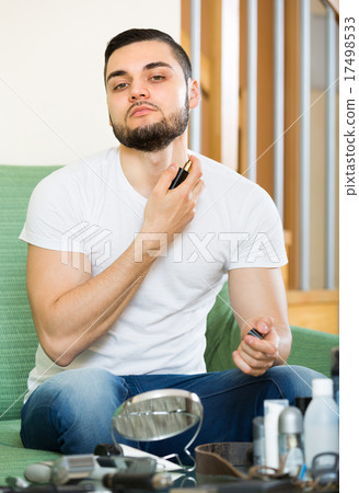 Young guy using perfume at home. 17498533