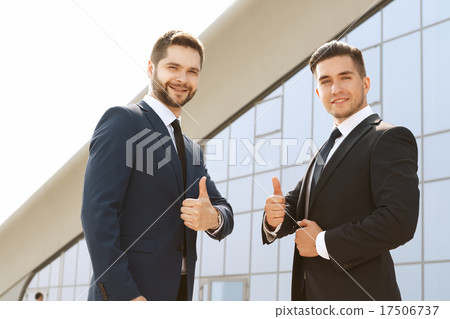 Smiling business partners giving a thumb's up 17506737