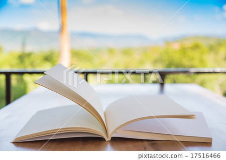 Open book on wood table in green forest ( moving page ) Open book on wood table in green forest ( moving page ) 17516466