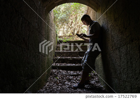 Young man works on a smart-phone in dark tunnel 17522769