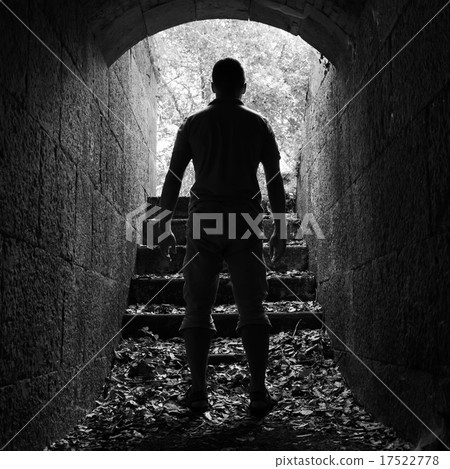 Young man stands in dark stone tunnel 17522778