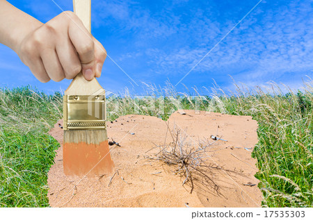 hand with paintbrush paints sand in green meadow hand with paintbrush paints sand in green meadow 17535303