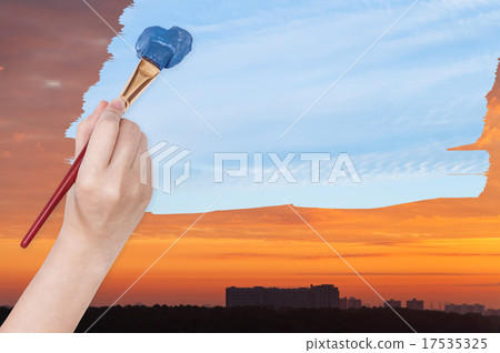 paintbrush paints blue day sky on orange sunset 17535325