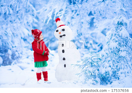 Little girl building snow man in winter 17537656