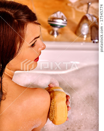 Woman using bath sponge in bathtub. 17545774