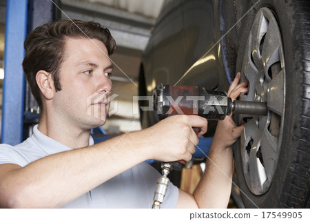 Mechanic In Garage Using Air Hammer On Car Wheel 17549905