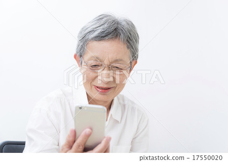 80-year old grandma who watches smart phone white back 17550020