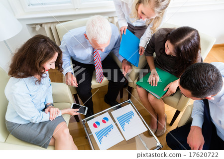 Five business people in team meeting studying graphs 17620722