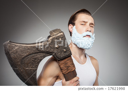 Cheerful young man is carrying axe during shaving 17621998