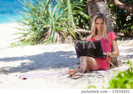 Blond girl with a laptop on tropical beach Blond girl with a laptop on tropical beach 17634891