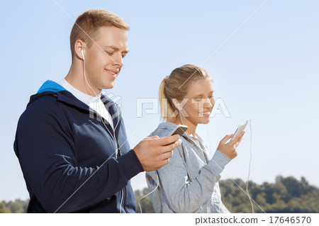 Two friends listening to music on their headphones 17646570