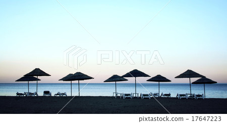 Line of straw umbrellas and sunbeds. Vintage image 17647223