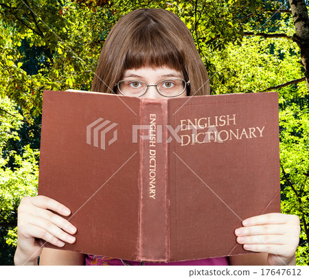 girl looks over English Dictionary and green woods girl looks over English Dictionary and green woods 17647612