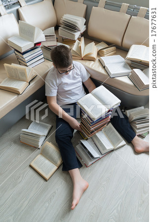 Tired boy sleeping surrounded by books in room Tired boy sleeping surrounded by books in room 17677631