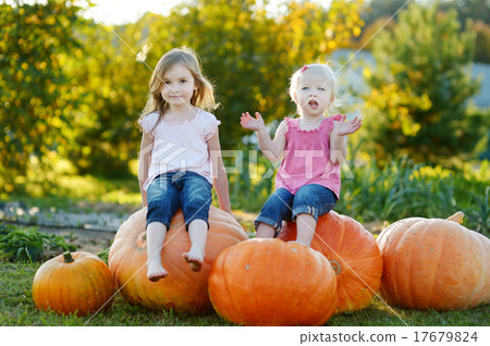 Two little sisters sitting on a huge pumpkins 17679824