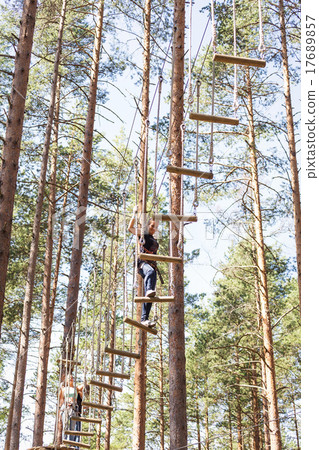 Young brave woman climbing in adventure rope park Young brave woman climbing in adventure rope park 17689857