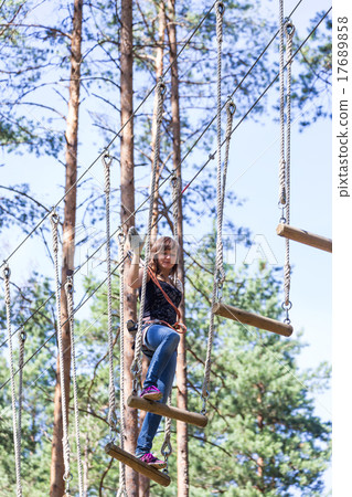 Young brave woman climbing in adventure rope park Young brave woman climbing in adventure rope park 17689858