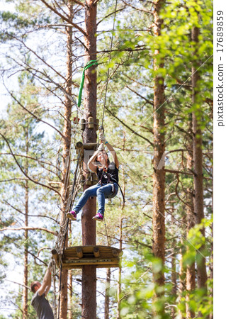 Young brave woman climbing in adventure rope park 17689859