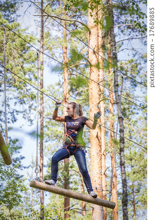 Young brave woman climbing in adventure rope park Young brave woman climbing in adventure rope park 17689885