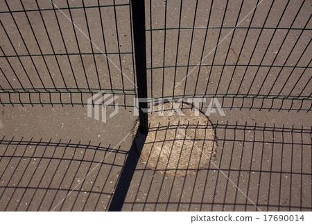 Metal fence and shadow on asphalt. 17690014