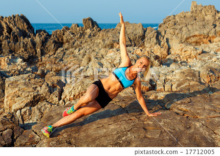 Athlete woman doing sport exercising on the rocks by the sea Athlete woman doing sport exercising on the rocks by the sea 17712005
