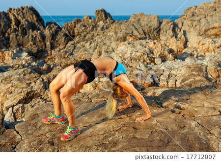 Athlete woman doing sport exercising on the rocks by the sea Athlete woman doing sport exercising on the rocks by the sea 17712007