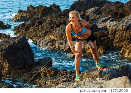 Athlete woman standing after sport exercising on the rocks by th Athlete woman standing after sport exercising on the rocks by th 17712008