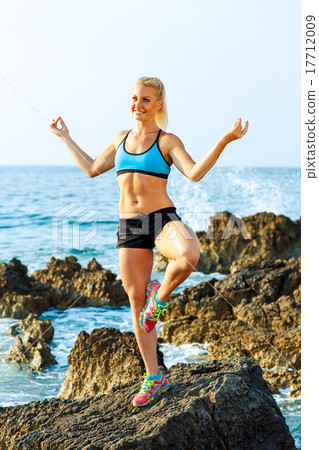 Athlete woman doing sport exercising on the rocks by the sea Athlete woman doing sport exercising on the rocks by the sea 17712009