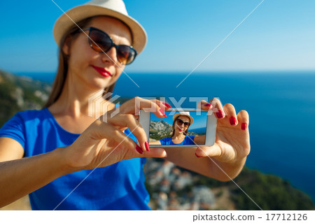 Girl in the hat making selfie by the smartphone on the backgroun Girl in the hat making selfie by the smartphone on the backgroun 17712126