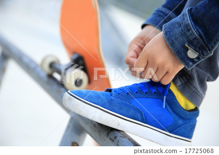 skateboarder tying shoelace at skate park 17725068