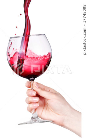 Glass of red wine with splashes in hand isolated 17748098