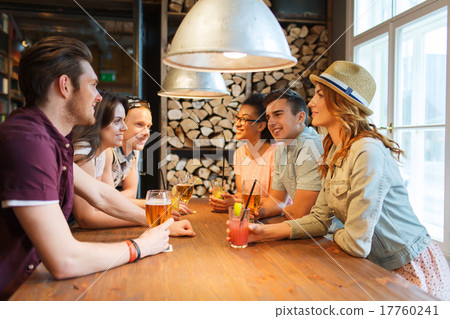 happy friends with drinks talking at bar or pub 17760241