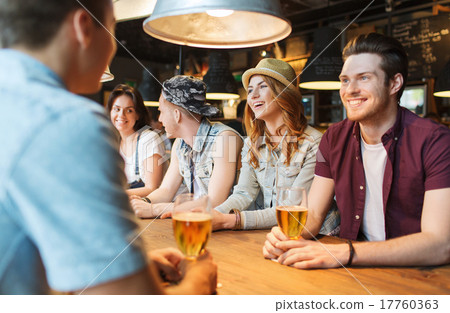 happy friends drinking beer and talking at bar 17760363