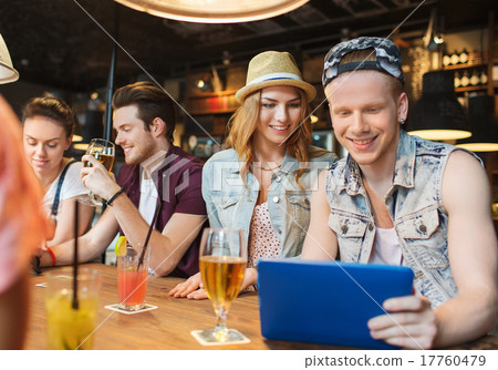 happy friends with tablet pc and drinks at bar 17760479