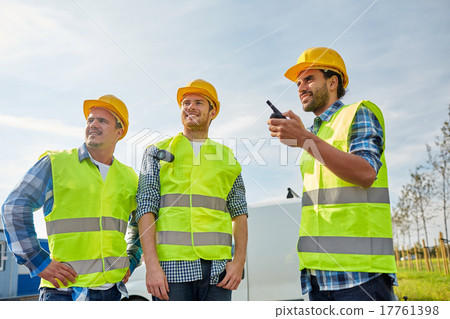 圖庫照片: happy male builders in vests with walkie talkie