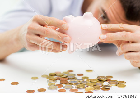 close up of man pouring coins from piggy bank close up of man pouring coins from piggy bank 17761848