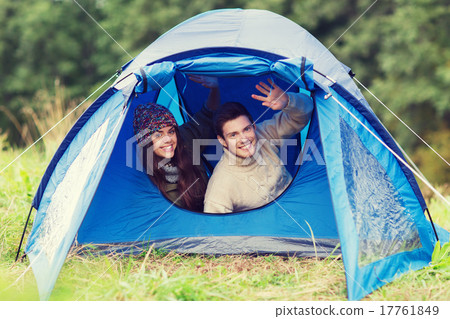 smiling couple of tourists looking out from tent smiling couple of tourists looking out from tent 17761849