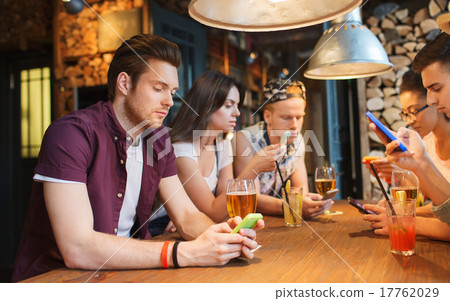 friends with smartphones and drinks at bar 17762029