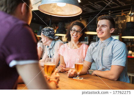 happy friends drinking beer and talking at bar 17762275